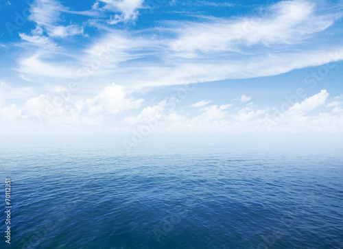 blue sea or ocean water surface with horizon and sky with clouds