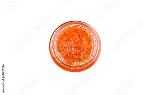 Orange fruit jam in a bottle over white background