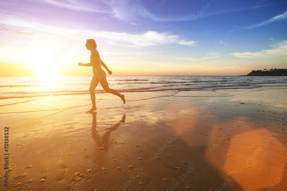 Silhouette of a girl running on ocean beach.