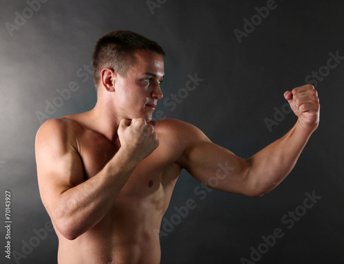 Handsome young muscular sportsman boxing on dark background © Africa Studio