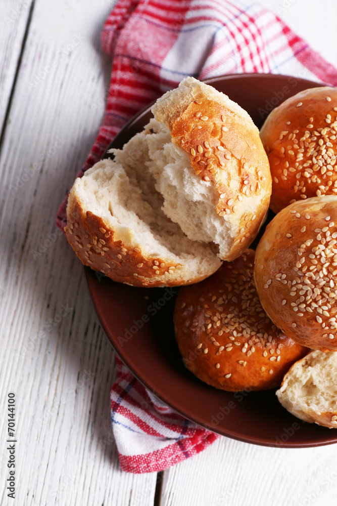 Tasty buns with sesame on plate, on color wooden background Tasty buns with sesame on plate, on color wooden background
