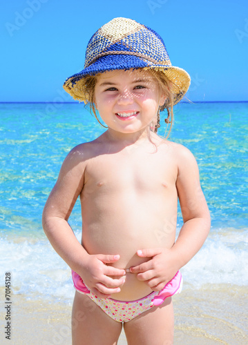 Bambina al mare con cappello azzurro