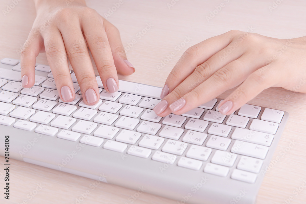 Female hands typing on keyboard on light background Female hands typing on keyboard on light background