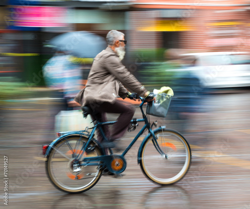 Cyclist in motion riding down the street on rainy day