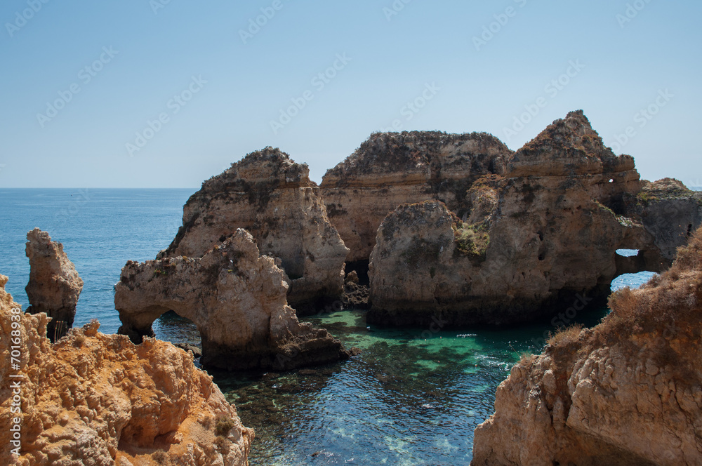Algarve coast, Portugal. Rocks in the shoreline and blue water