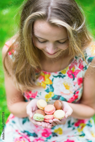 Young girl holding French macaroons in hands