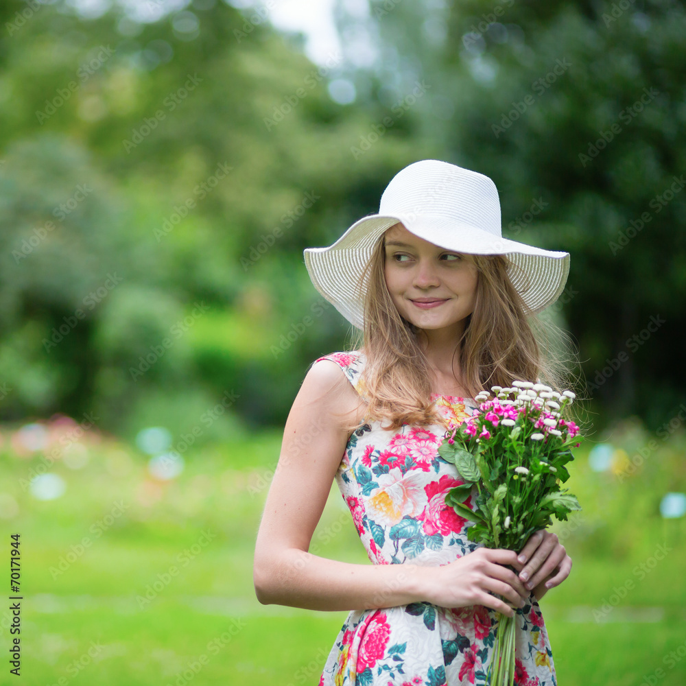 Young girl in white hat holding flowers