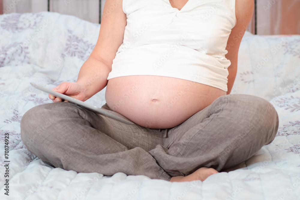 Pregnant woman reading book on a tablet Pregnant woman reading book on a tablet