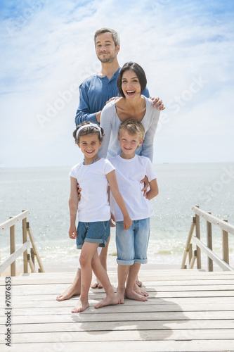 happy family standing on a wood pontoon in front of the sea in