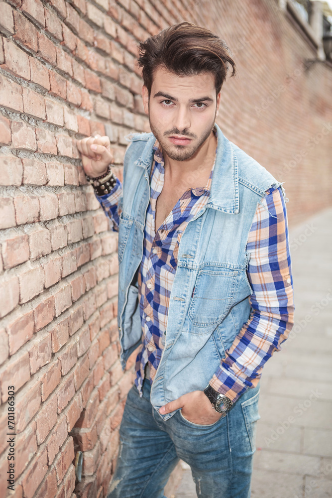 man posing for the camera near a brick wall man posing for the camera near a brick wall