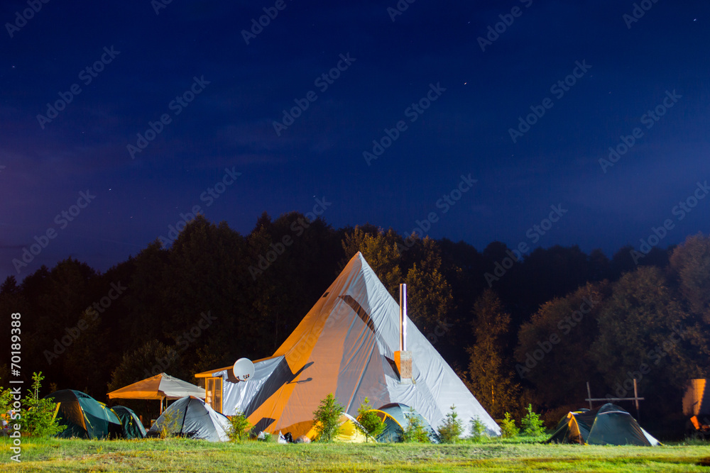 Tents in the tourist camp in a forest glade. Night.