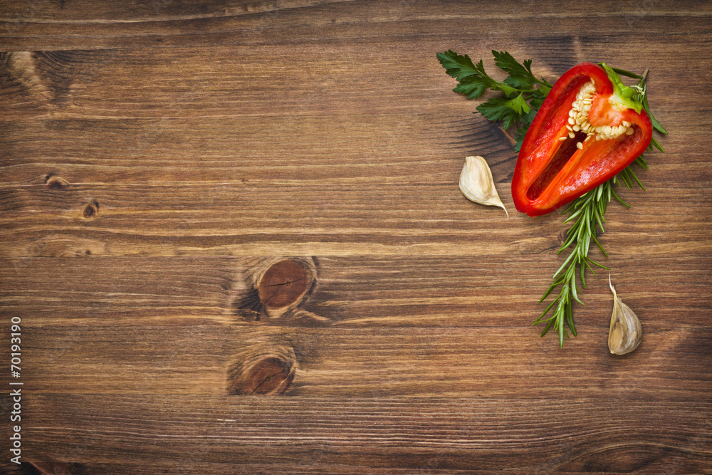 Pepper and garlic in greens on wooden board with copyspace