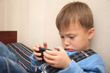 child lying and playing on smartphone