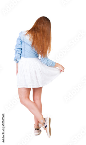 Fotografie back view of standing young beautiful  woman makes a curtsey.