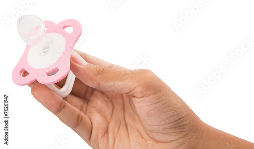 Fotografie Female hand holding pink pacifier over white background