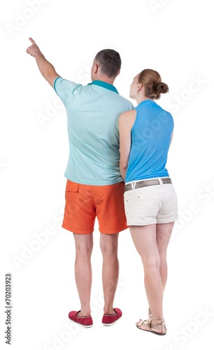 young couple in short pointing at wal