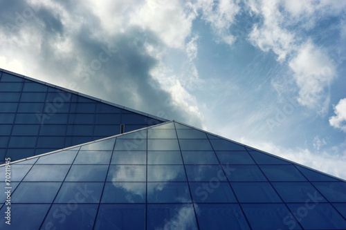 The glass panels of a building with reflection of clouds