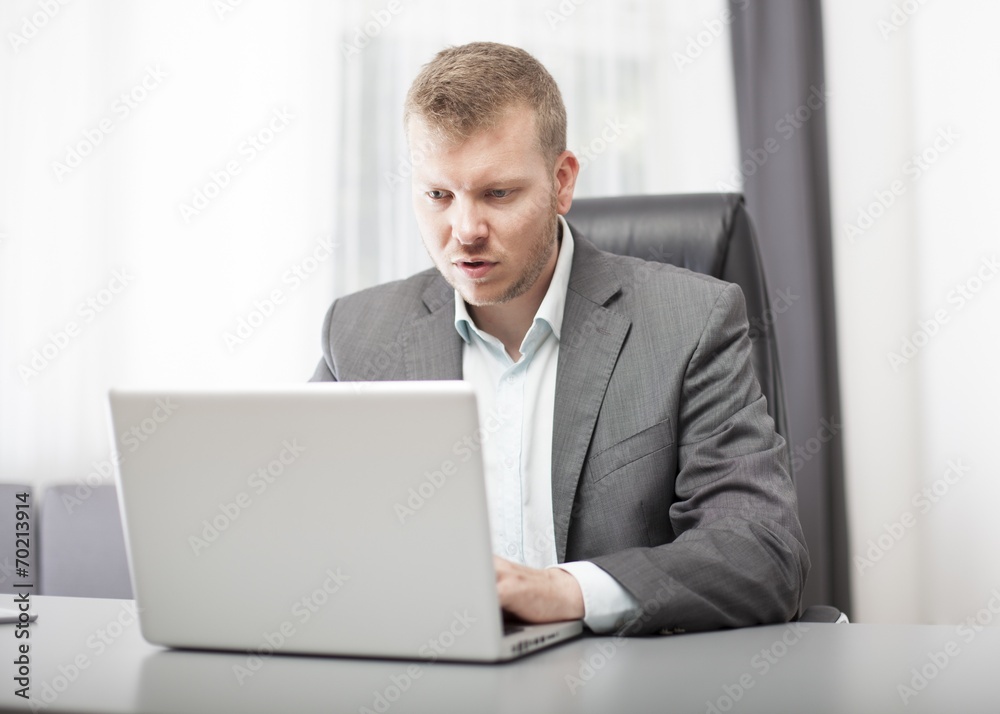 Businessman looking at his laptop in disbelief Businessman looking at his laptop in disbelief