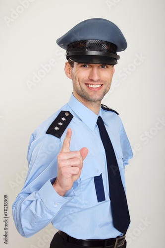 Smiling policeman shows with his finger on you