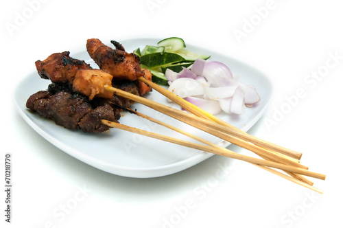 Delicious satay with cucumbers and onions served on white plate