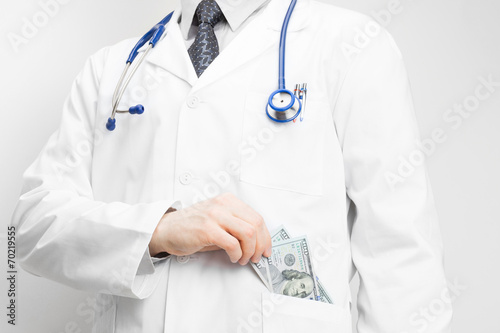 Doctor putting money into his pocket with his left hand