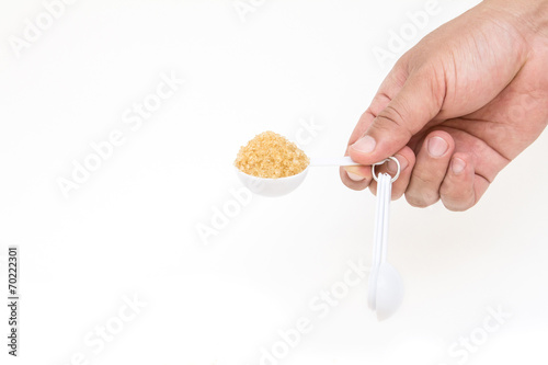 hand picking up brown sugar with measuring spoon