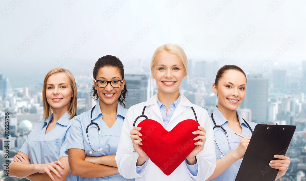 smiling female doctor and nurses with red heart - obrazy, fototapety, plakaty 
