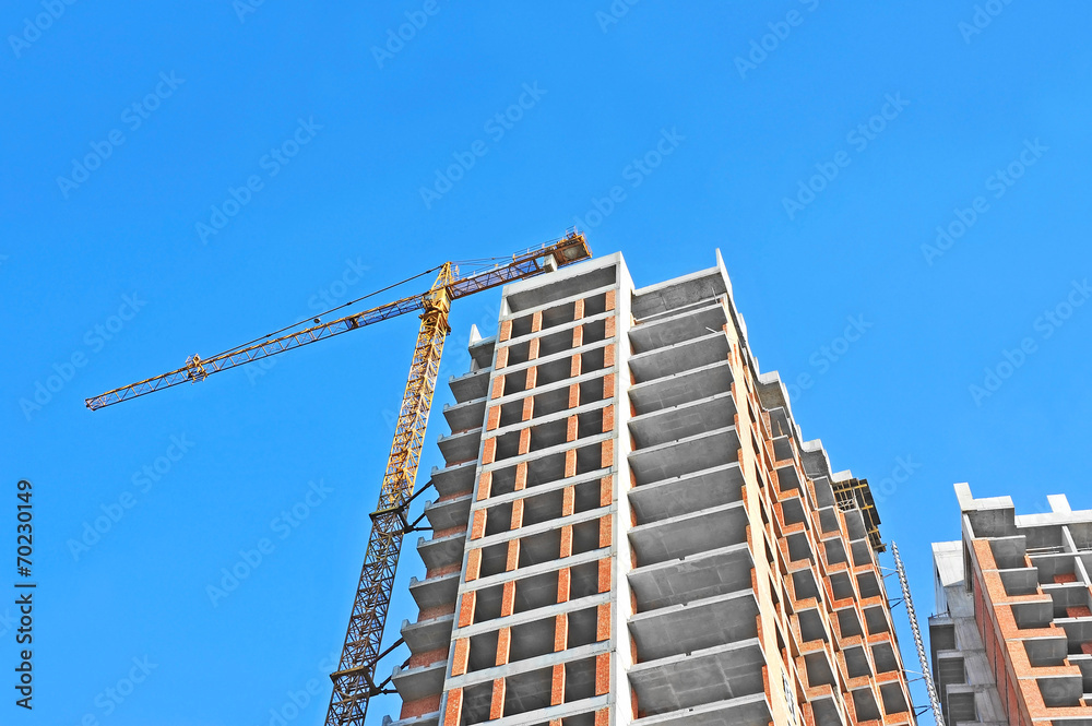 Crane and building construction site against blue sky Crane and building construction site against blue sky