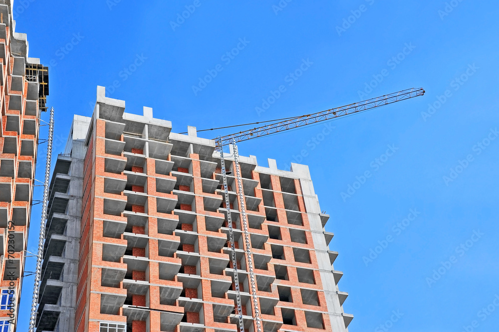 Crane and building construction site against blue sky Crane and building construction site against blue sky
