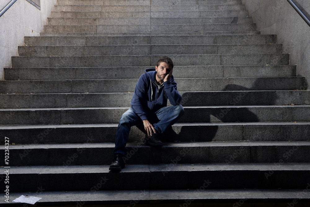 Young wasted man in depression sitting on ground street stairs Young wasted man in depression sitting on ground street stairs