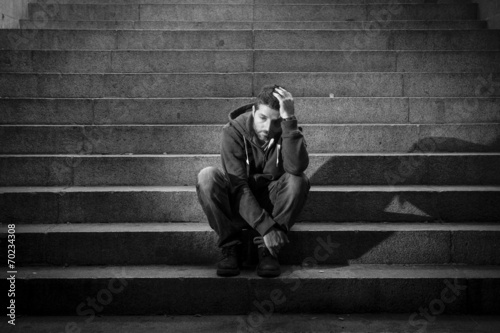 Young man jobless in depression sitting homeless on street