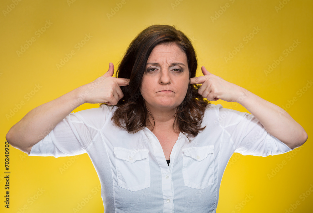 Fototapeta premium Woman plugging ears annoyed by loud noise ignoring someone