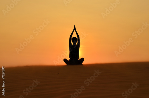 Women silhouette who practices yoga at sunset in sundunes
