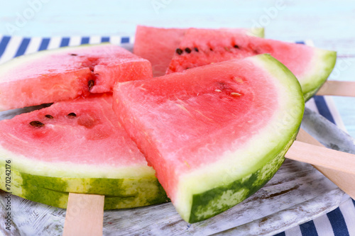 Slices of watermelon on tray on napkin on wooden background