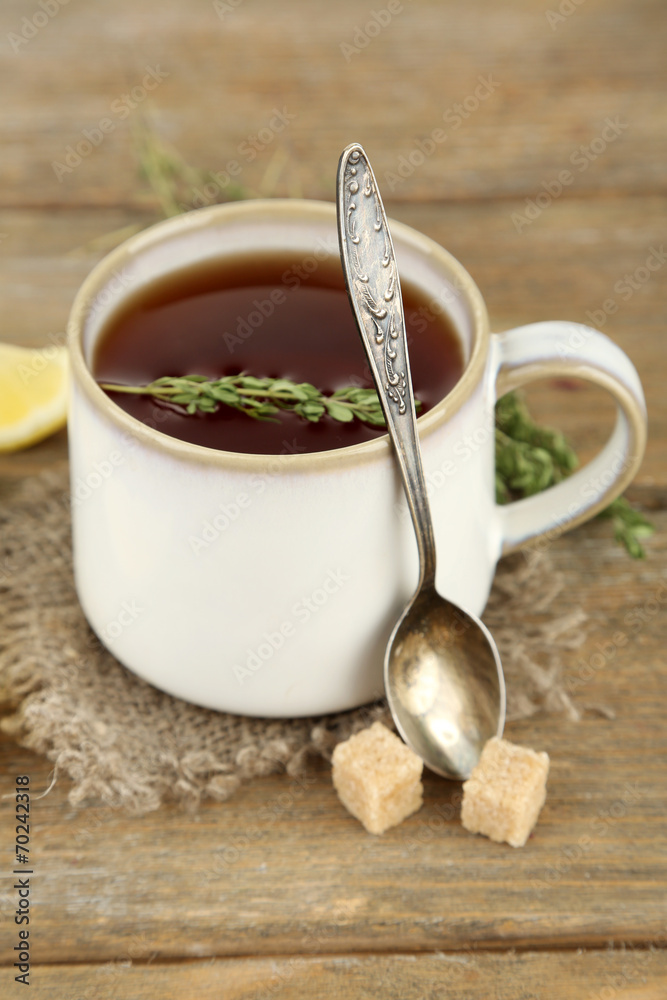 Cup of tasty herbal tea with thyme and lemon on wooden table Cup of tasty herbal tea with thyme and lemon on wooden table