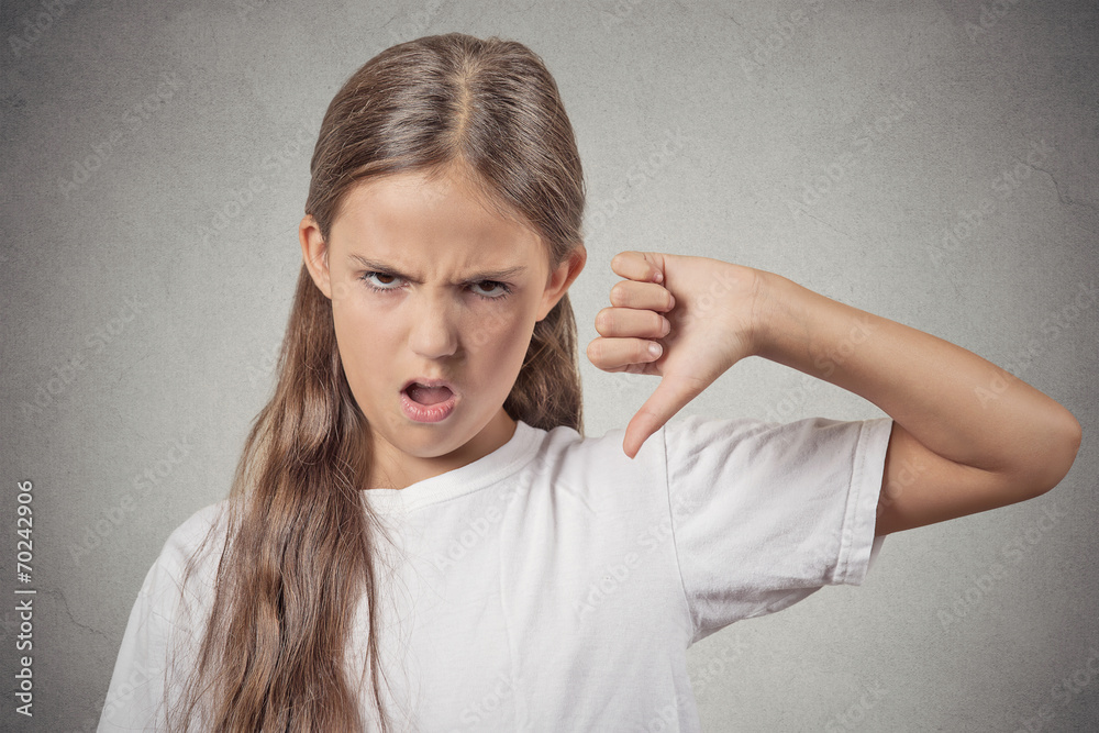 Thumbs down. I don't like it. Angry girl on grey background Thumbs down. I don't like it. Angry girl on grey background