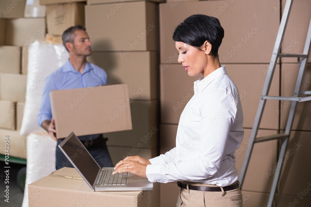 Pretty warehouse manager using laptop Pretty warehouse manager using laptop