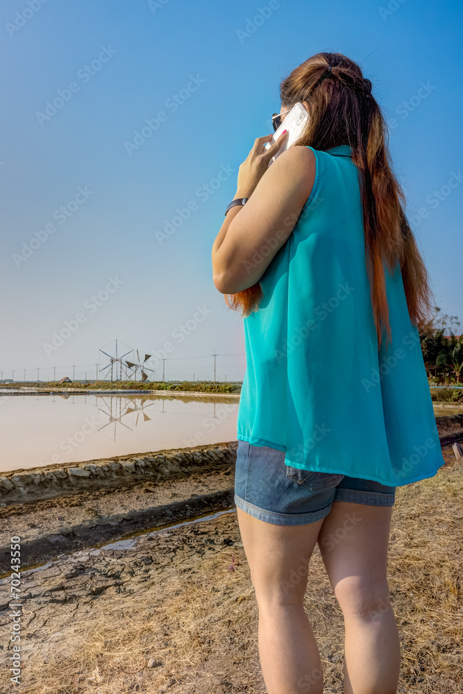 Woman at outdoor salt field using mobile phone Woman at outdoor salt field using mobile phone