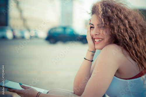 Smiling young woman using digital tablet on street