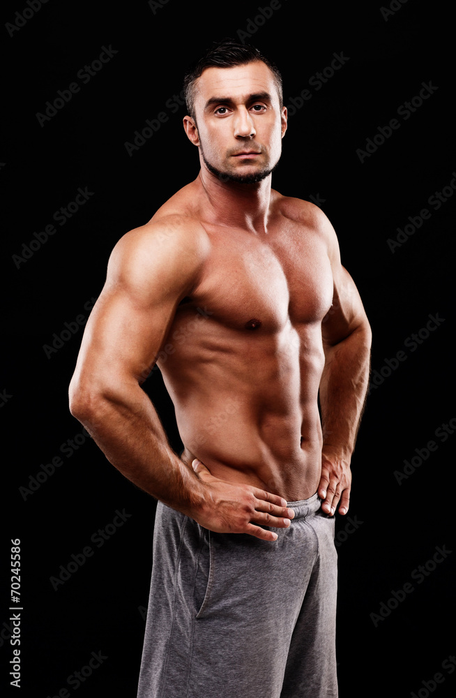 Serious muscular sportsman over black background