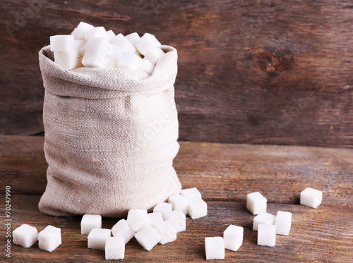 Refined sugar in bag on wooden background