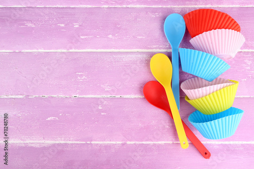 Plastic bowls and spoons on color wooden background