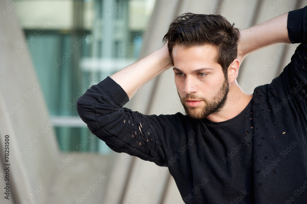 Handsome male fashion model posing with hands behind head Handsome male fashion model posing with hands behind head