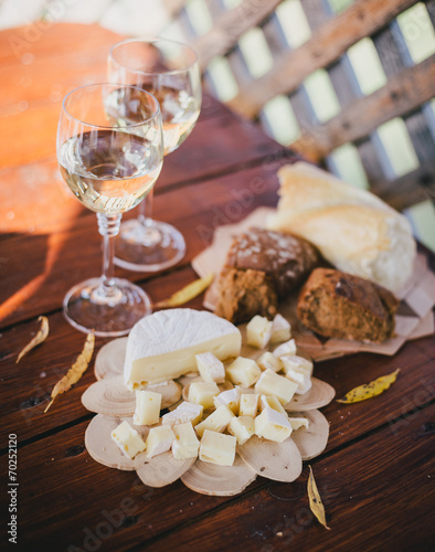 two glasses of white wine with cheese and bread on a table