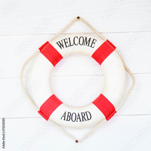 White Life buoy with welcome aboard on white wall