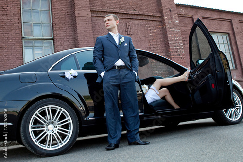 Wedding. Groom next to an executive car which sits bride. © 8th