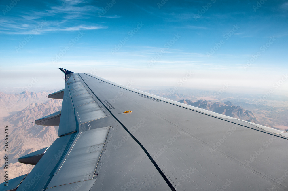 Wing of an airplane flying over mountains