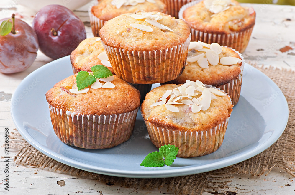 Muffins with plums and almond petals decorated with mint leaves Muffins with plums and almond petals decorated with mint leaves