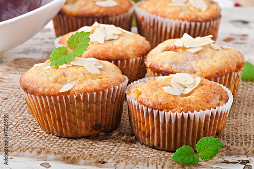 Muffins with plums and almond petals decorated with mint leaves