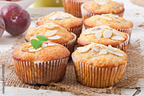 Muffins with plums and almond petals decorated with mint leaves